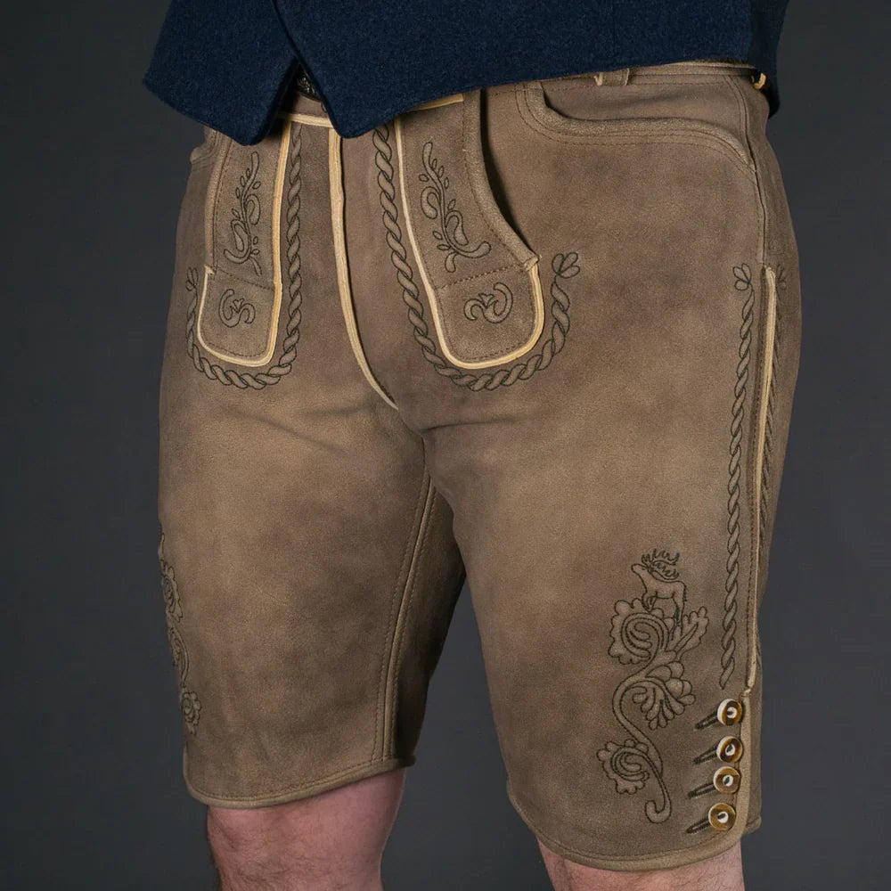 Moderner bayerischer Mann trägt eine kurze Wildbock Lederhose aus hochwertigem Wildleder mit feinen Reliefstickereien, kombiniert mit einem weißen Trachtenhemd – Datschi Trachten Kollektion